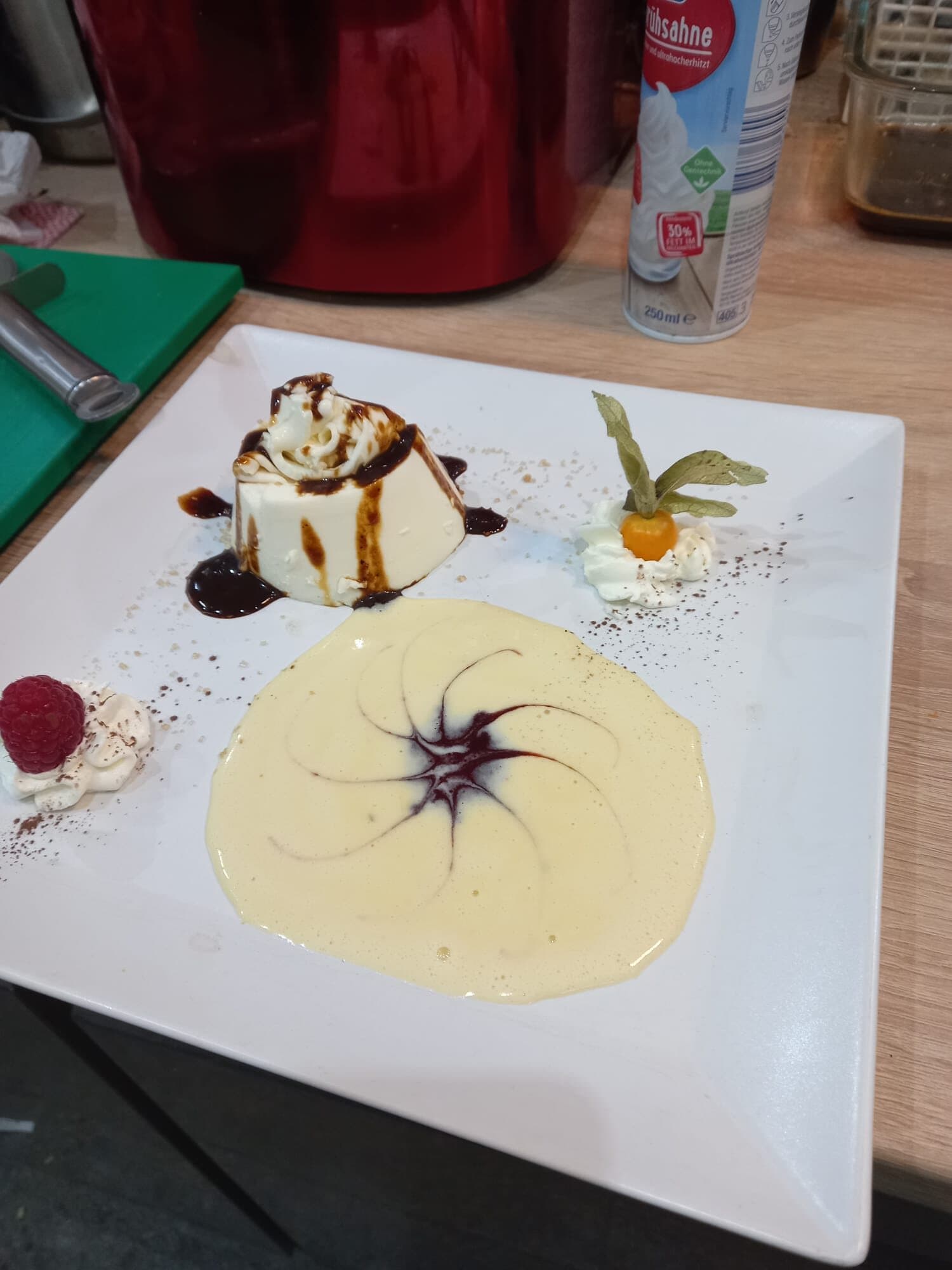 Dessertteller mit Panna cotta, Schokoladensauce, Physalis, Himbeere und Vanillecreme mit Spiralmuster